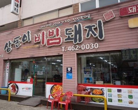 상돈이비빔돼지 외관 — 간판과 가게 앞 붉은 의자